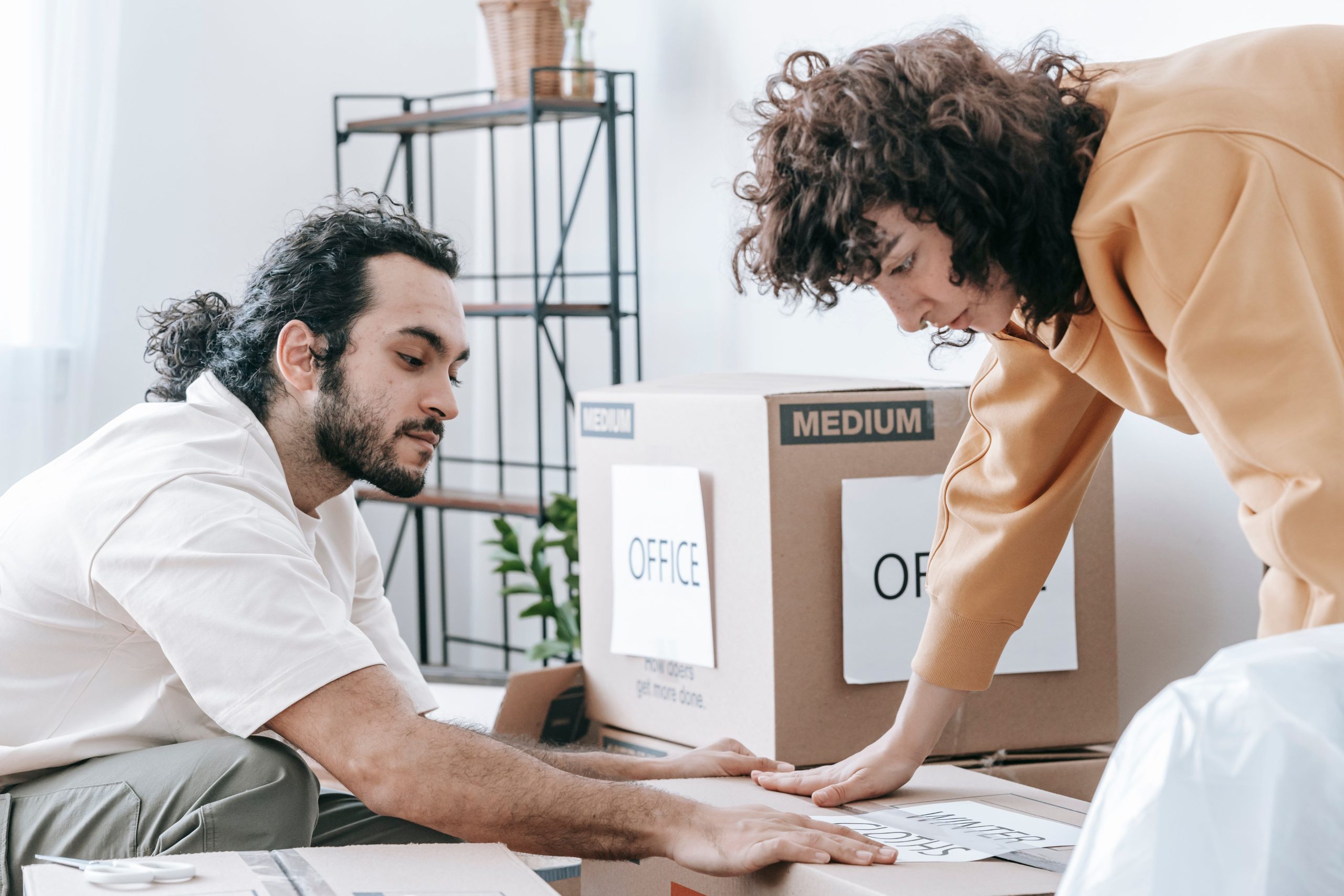 Couple emballant fournitures bureau dans cartons