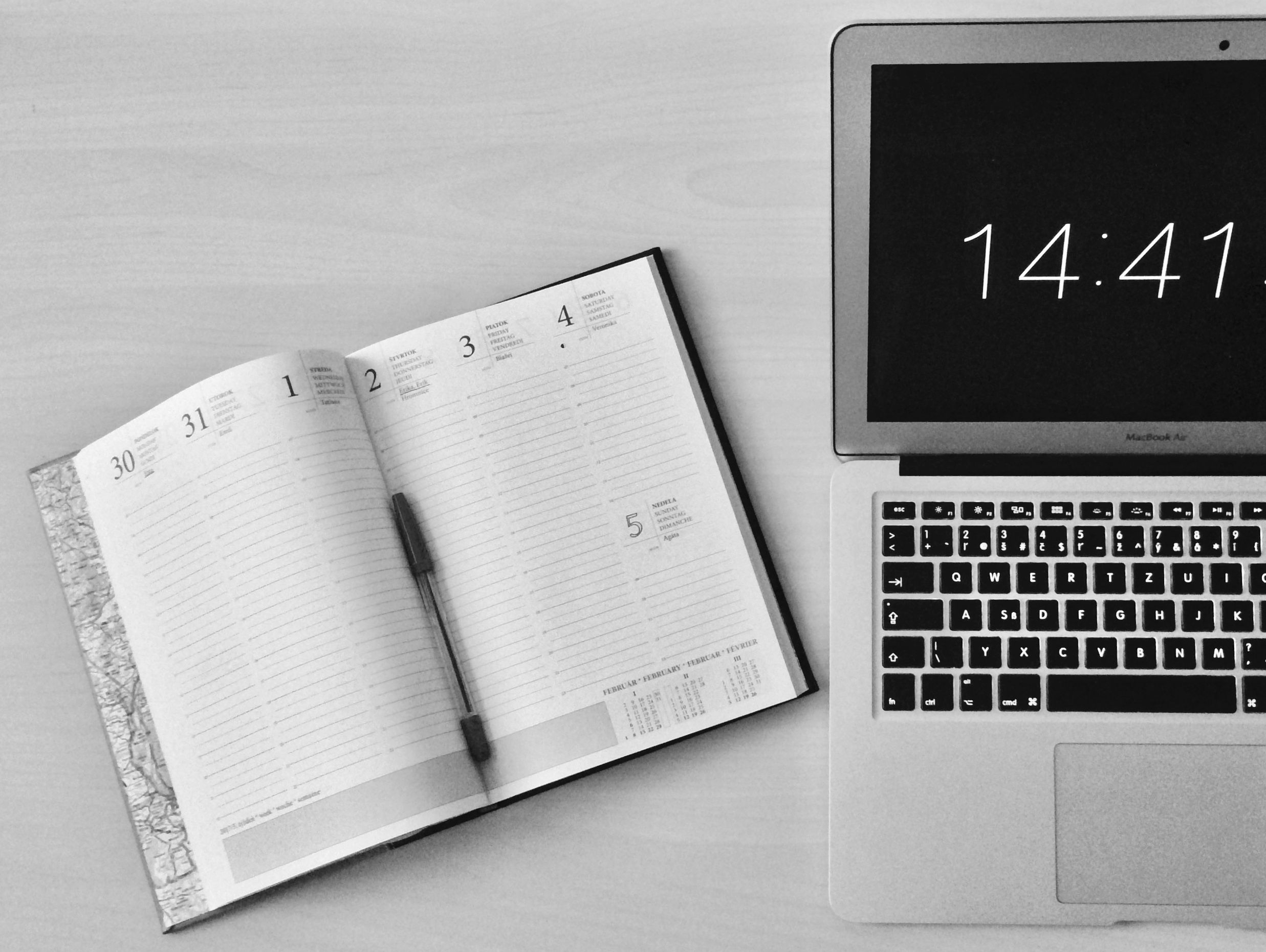 Bureau minimaliste avec notebook et MacBook affichant l'heure