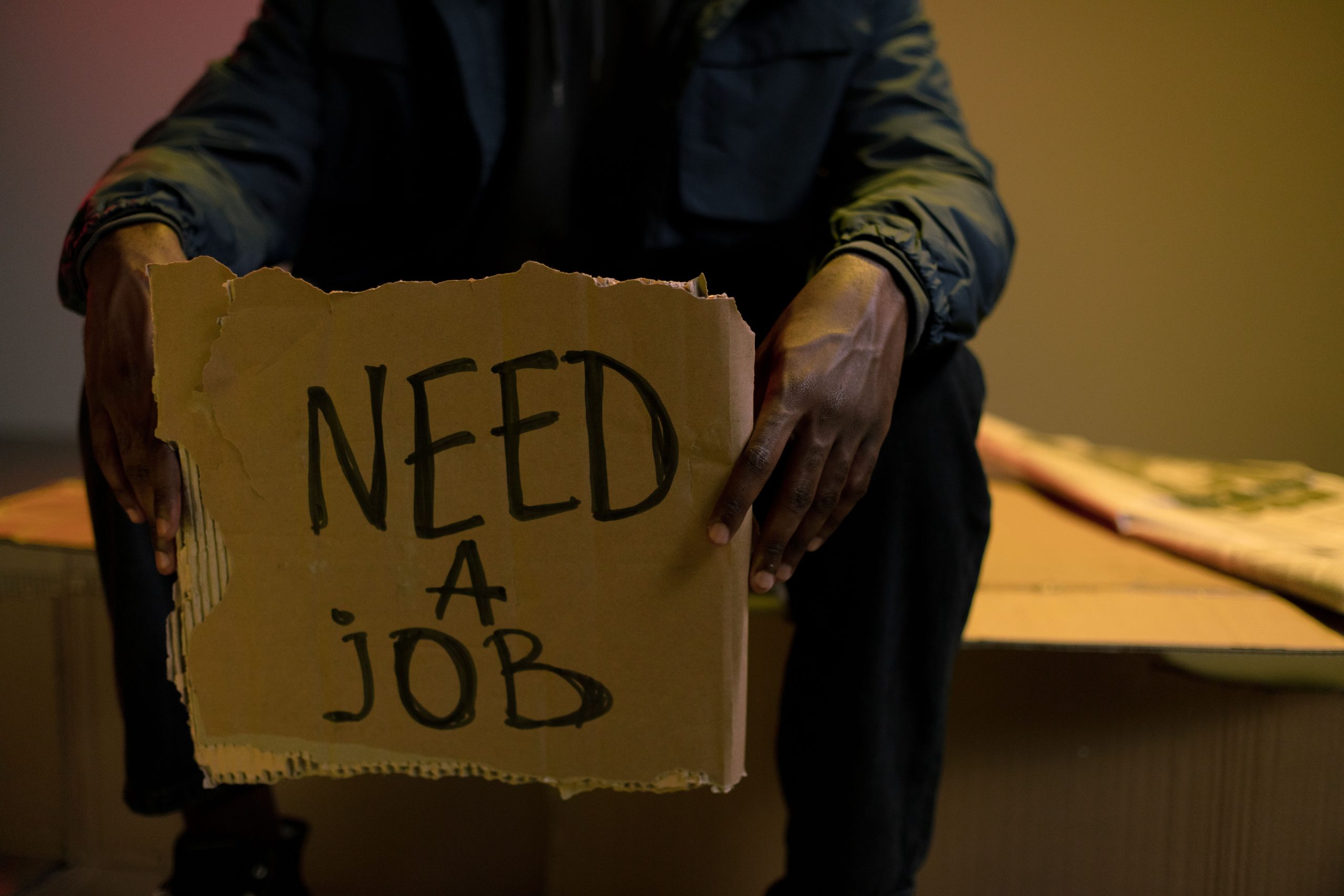 Homme avec panneau besoin travail chômage