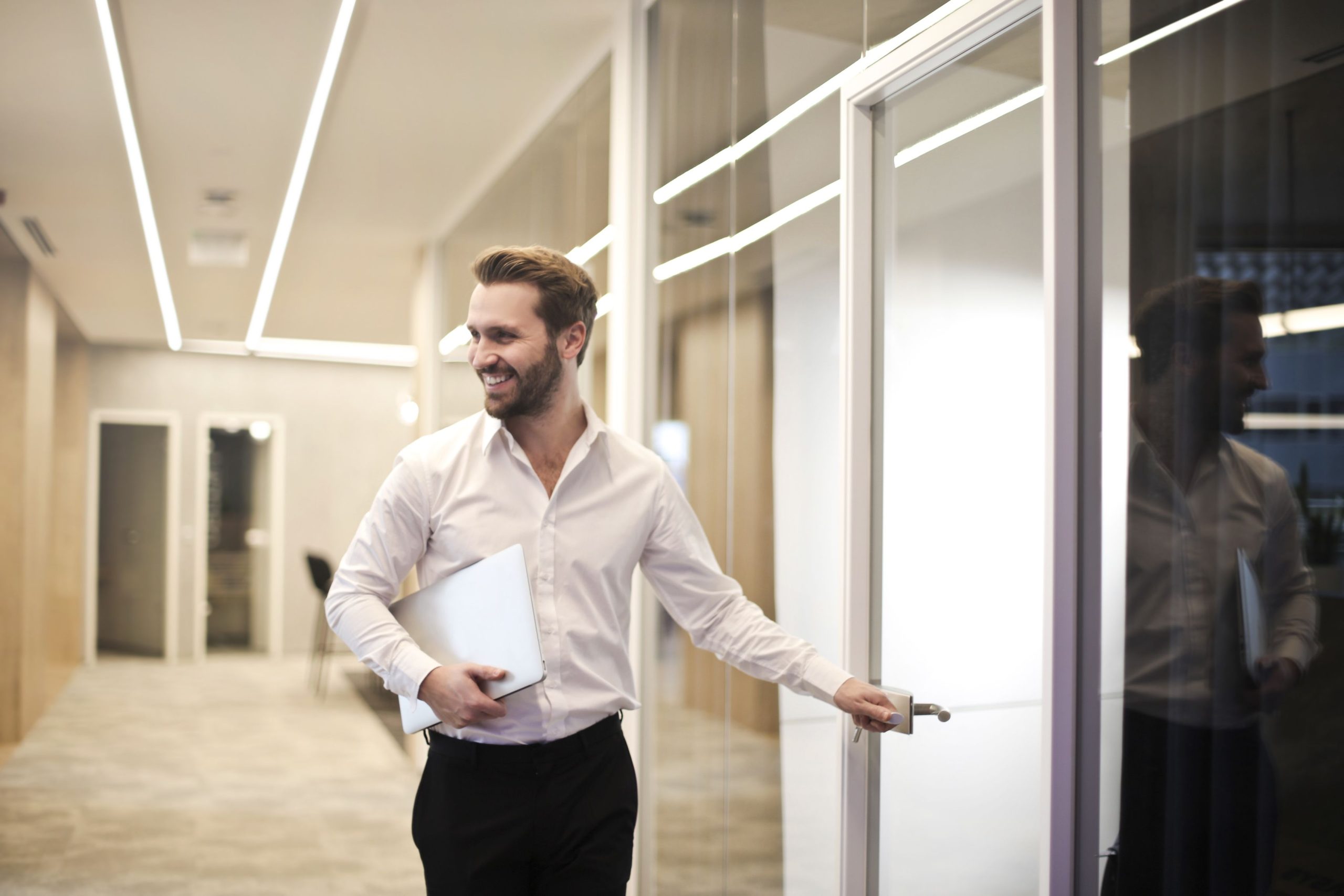 Homme souriant avec ordinateur portable en bureau moderne