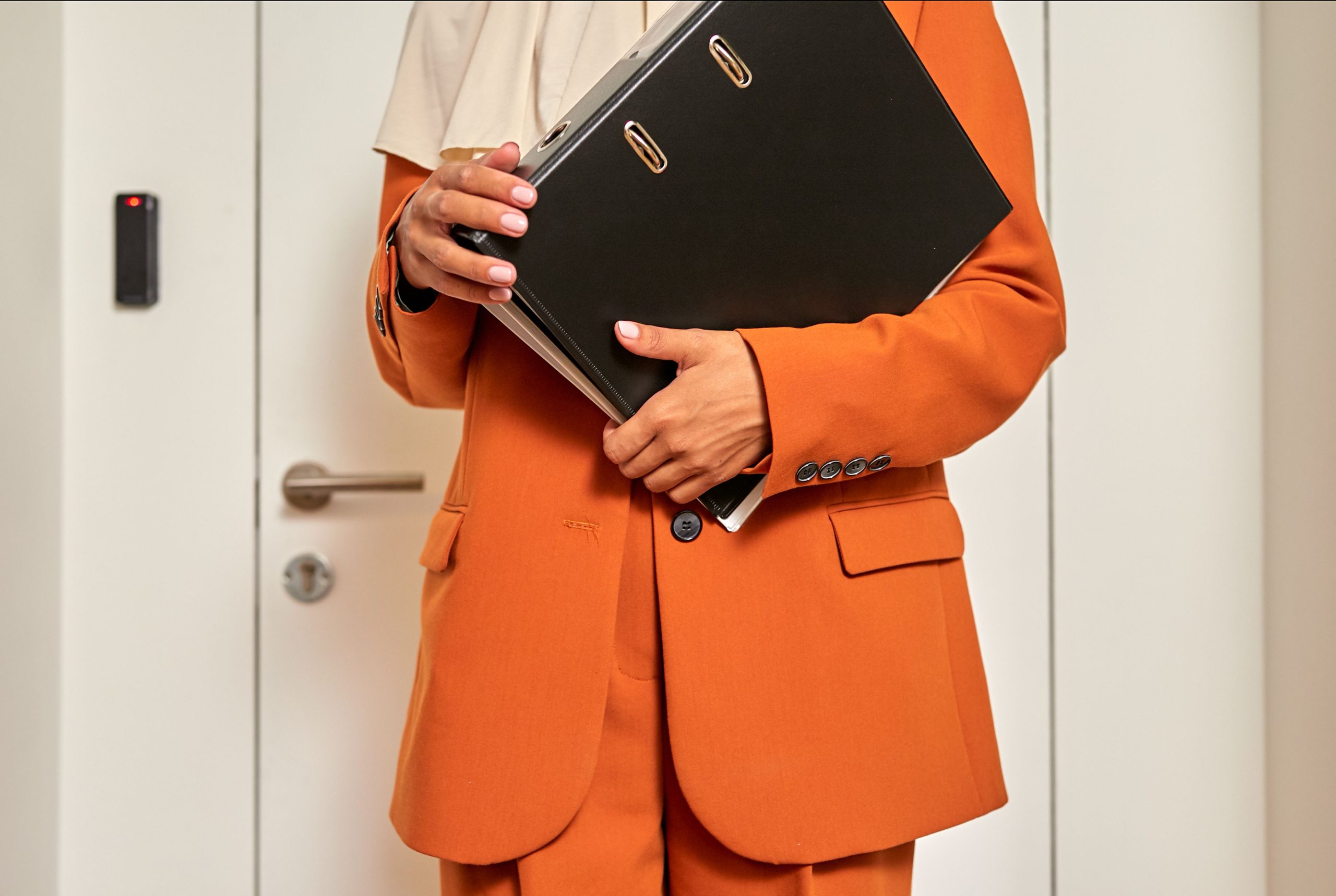 Assistante tenant un dossier devant une porte fermee