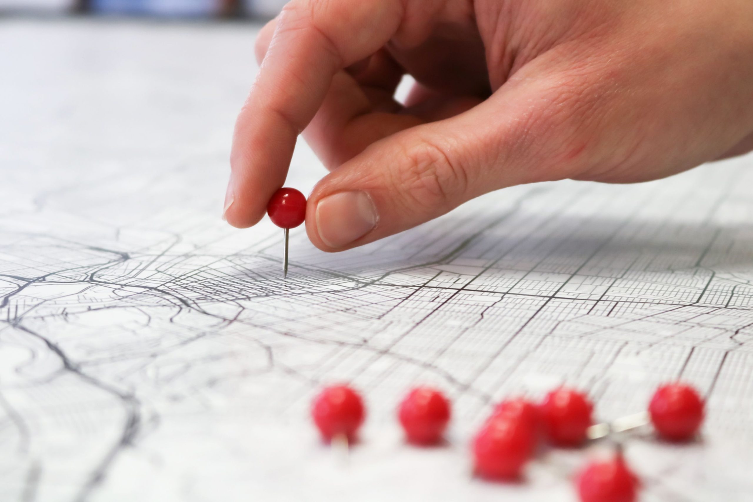 Main plaçant épingle rouge sur carte géographique