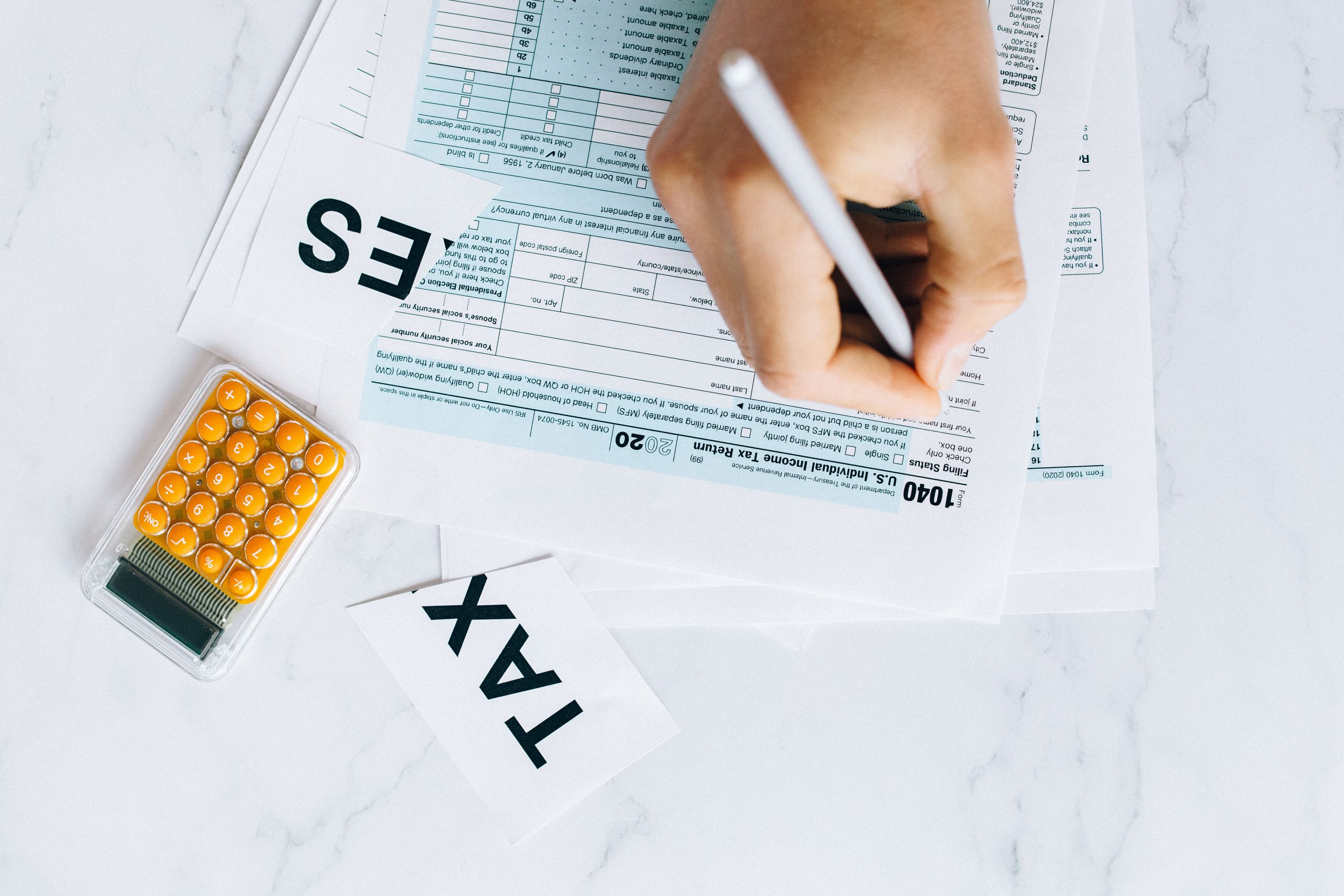 Main écrivant sur formulaire fiscal avec calculatrice