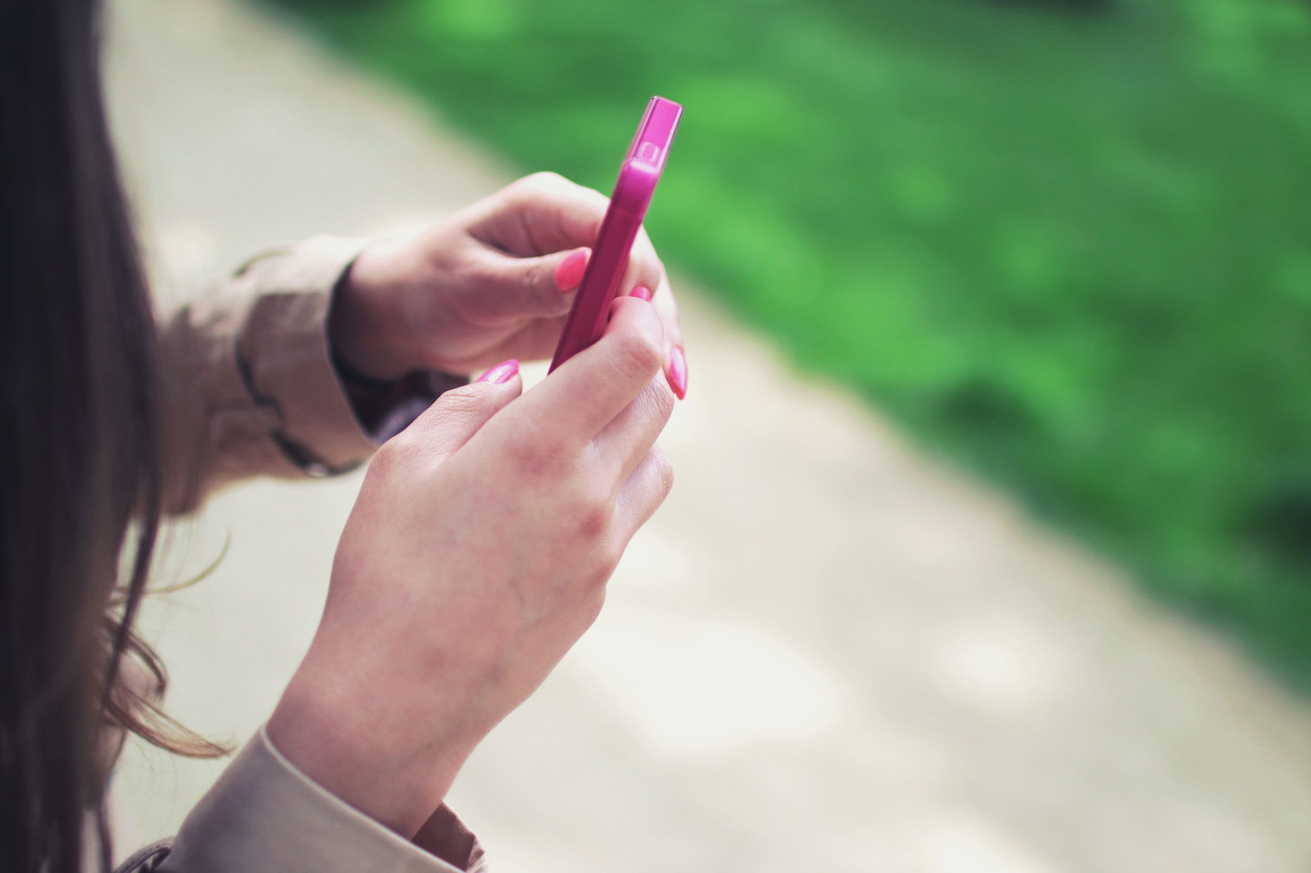 Femme tenant smartphone rose en extérieur