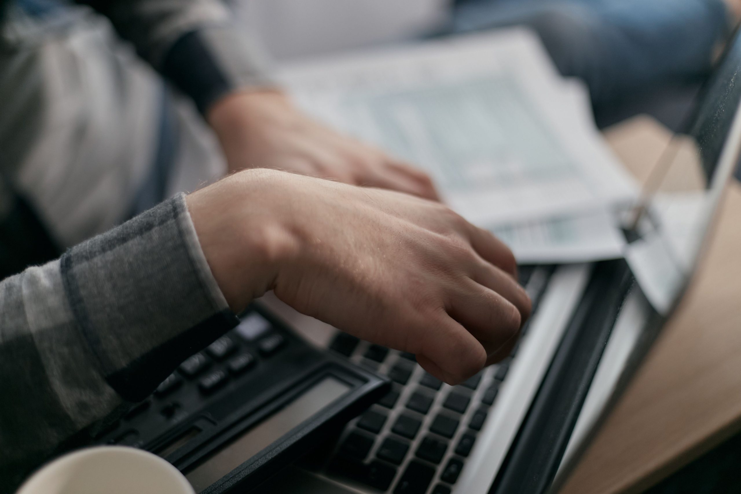 Mains calculant finances avec ordinateur et documents