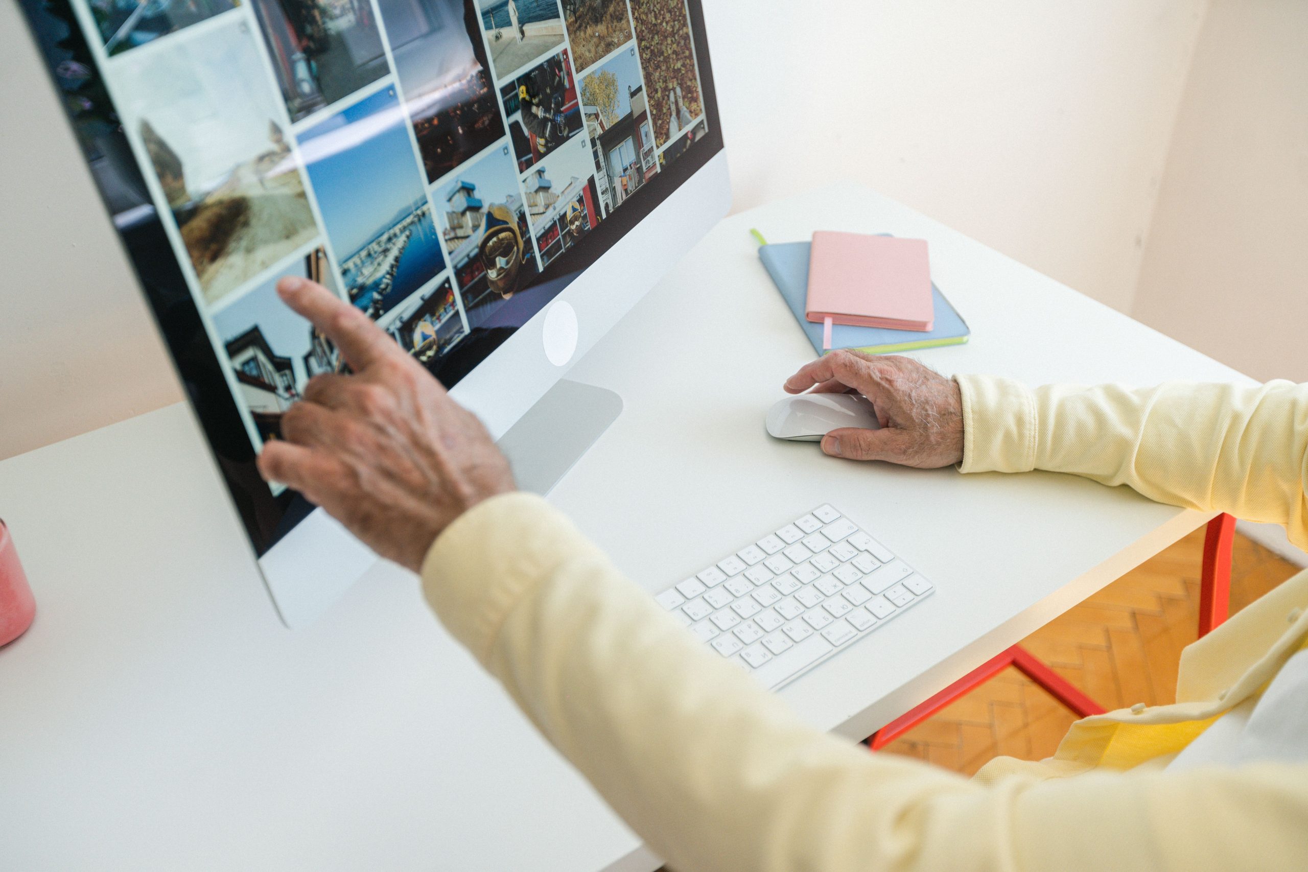 Adulte senior parcourant des photos sur un ordinateur de bureau.