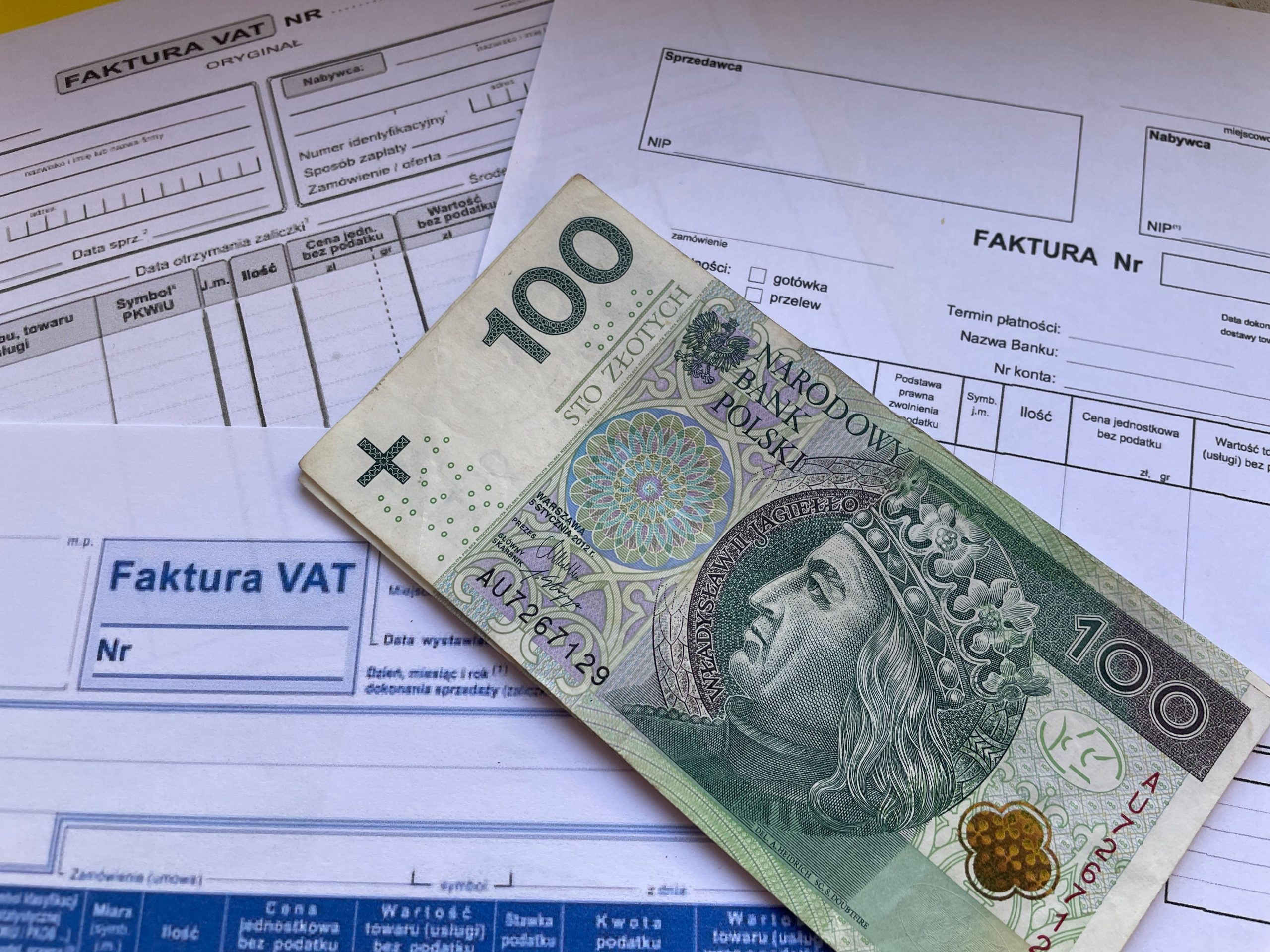 Billets de banque posés sur des factures professionnelles