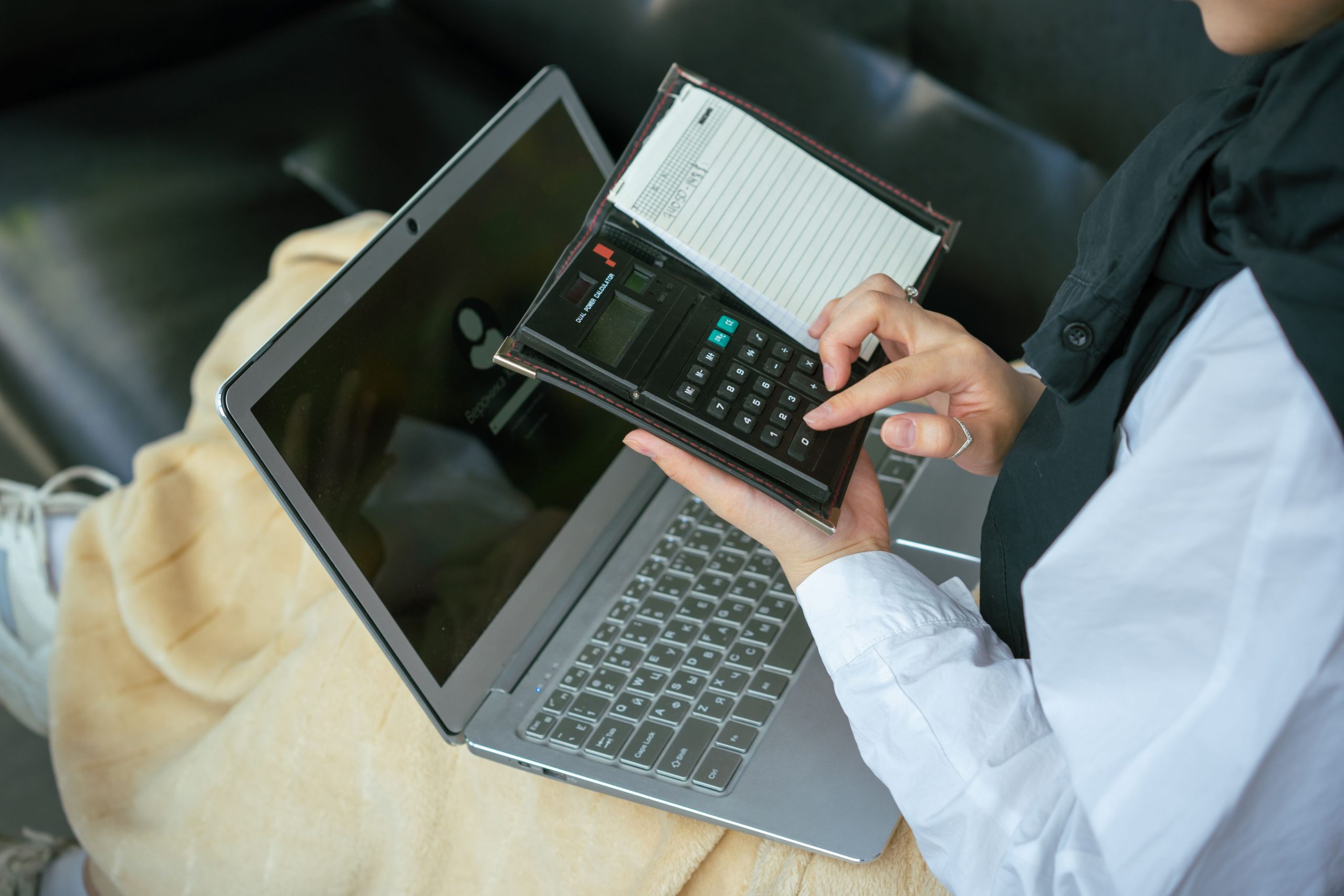 Personne utilisant une calculatrice près d'un ordinateur portable