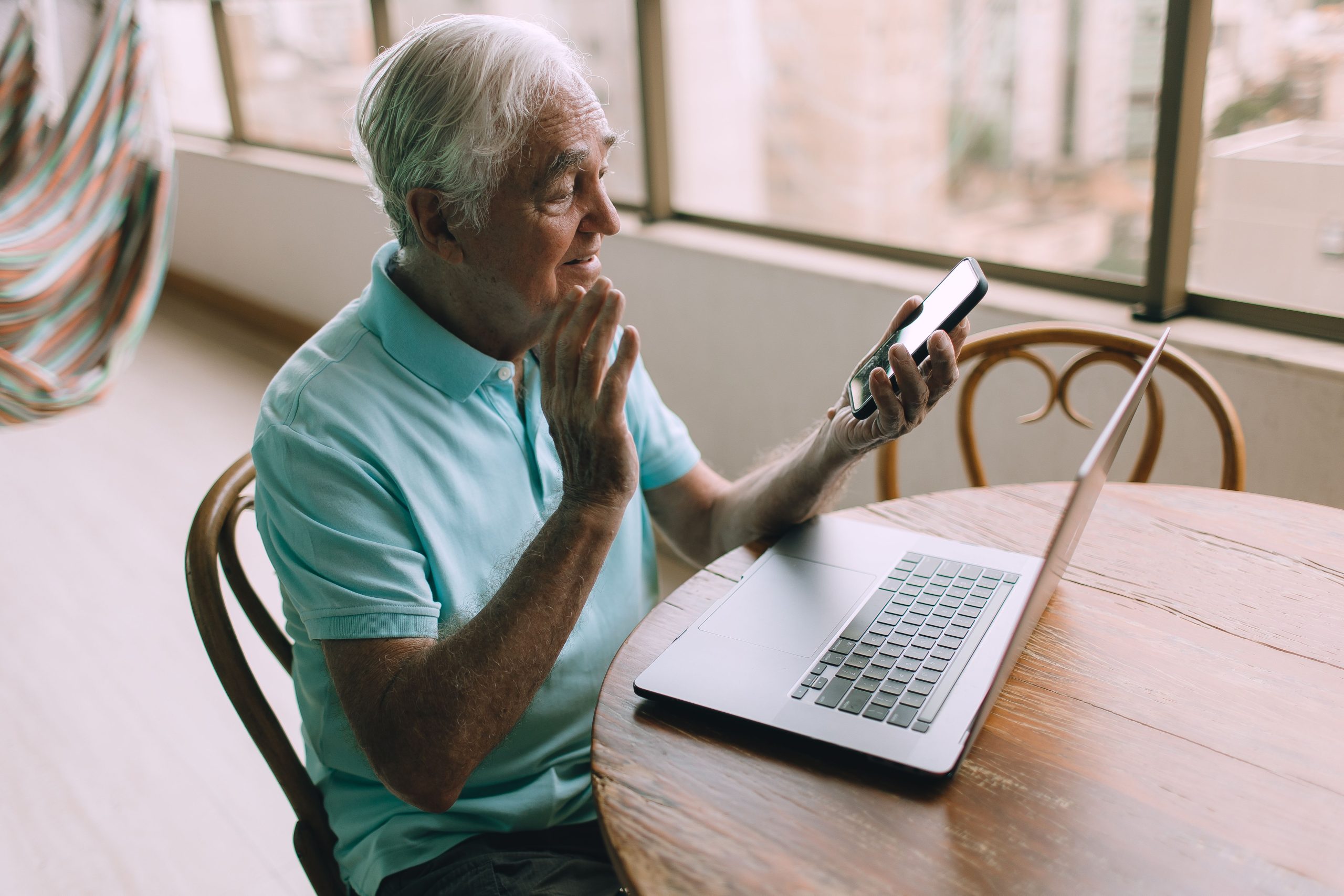 Homme senior en visio smartphone et laptop